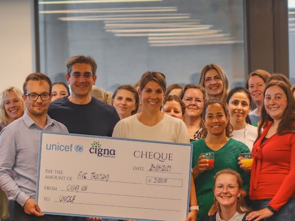Belgium employees posing in front of a donation check to unicef
