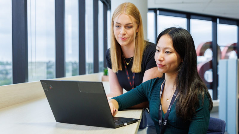 Two female corporate team members using a laptop together in the Coles SSC 