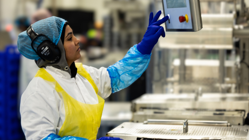 A female Coles employee operating machinery in a Retail Manufacturing site.