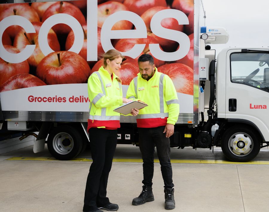 Two Customer Fulfilment Centre team members working in the loading dock at the in front of a Coles branded delivery van