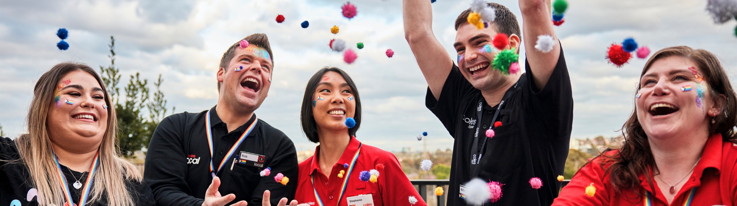 Coles employees celebrating pride with rainbow ball confetti 