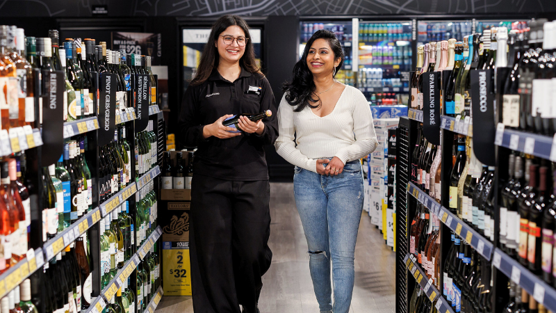 A female liquorland team member walking through the store with a customer