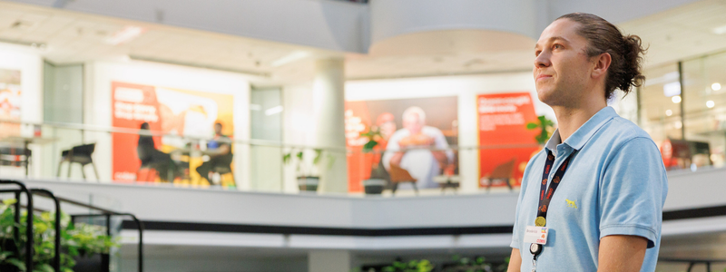 A male graduate standing in the middle of Coles Store Support Centre. 