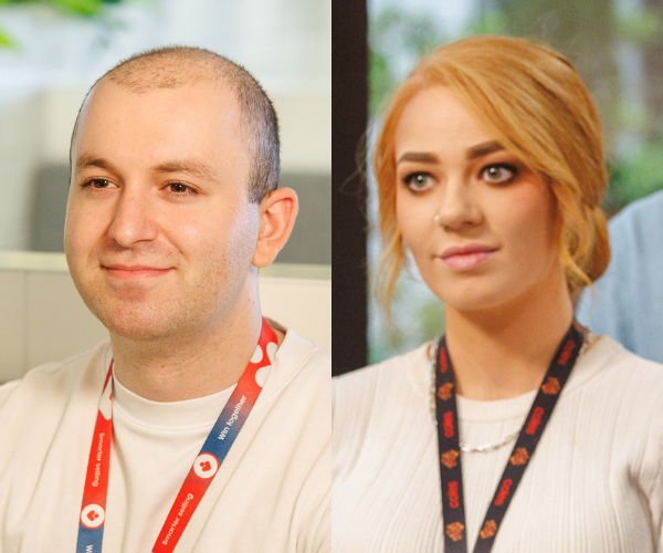 Two team members wearing company lanyards and light-coloured tops, seated in a modern office environment with a bright and open background.