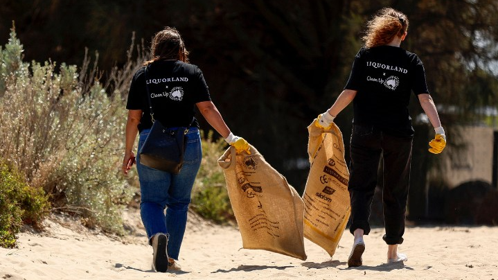 Two Liquorland team members picking up rubbish on a beach