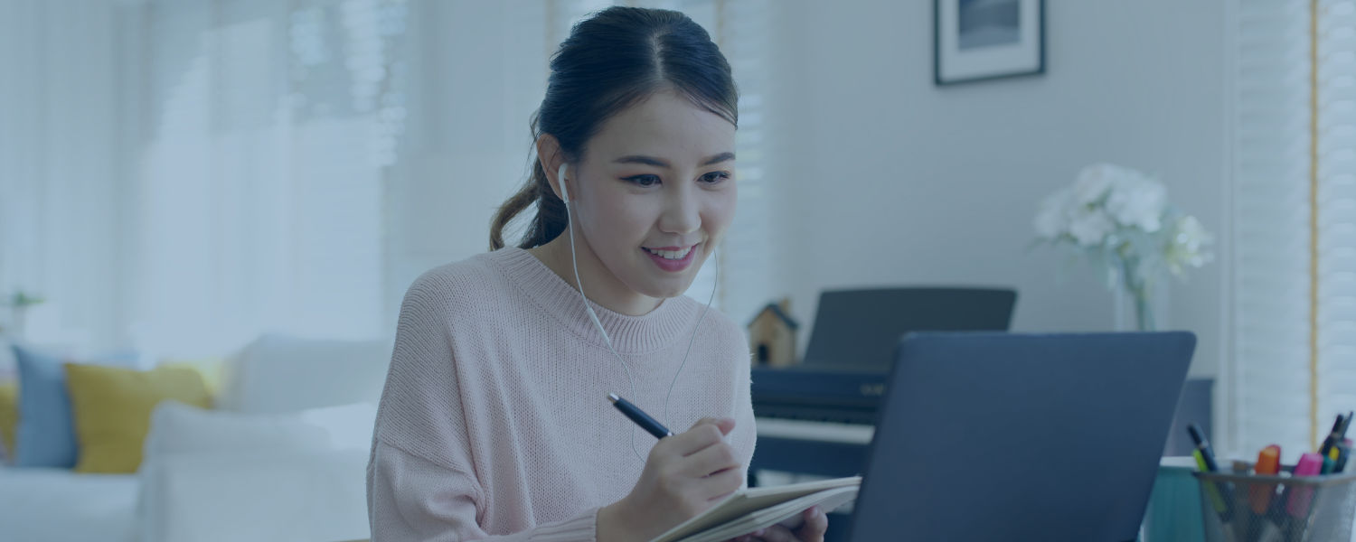 Student with headphones taking notes in front of computer