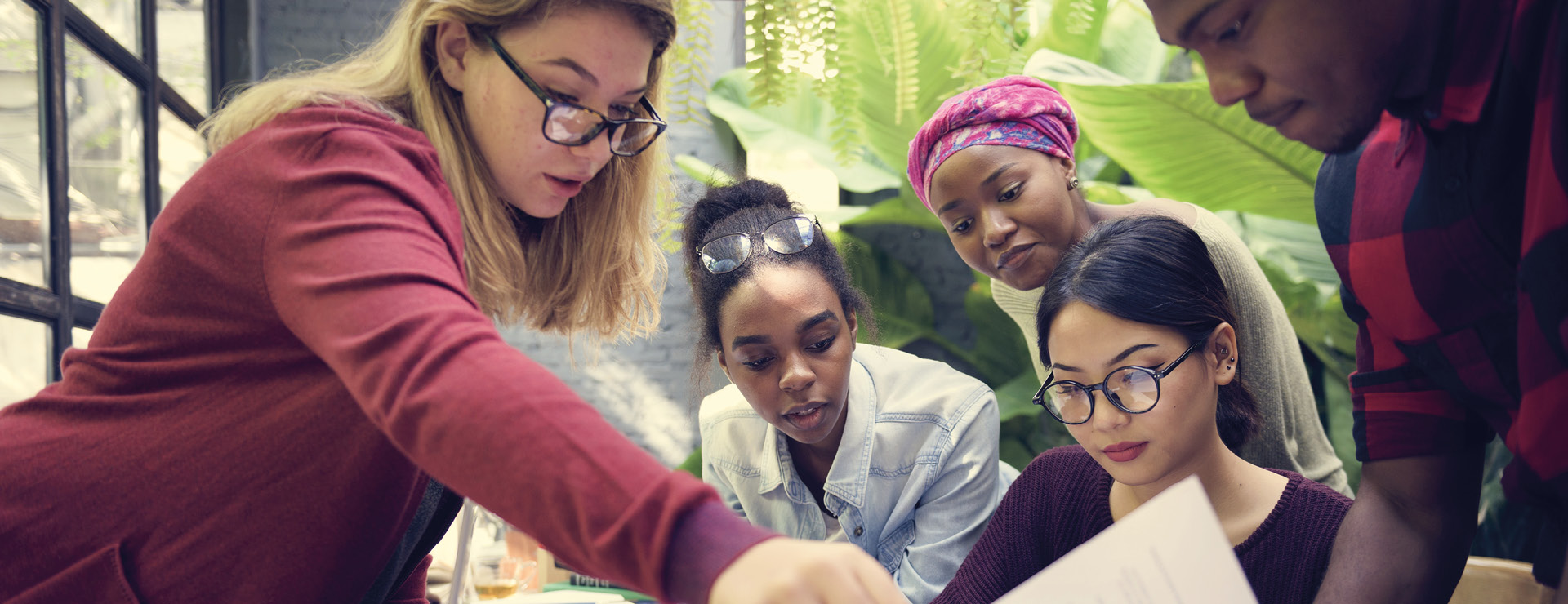 5 students looking at documents on a table