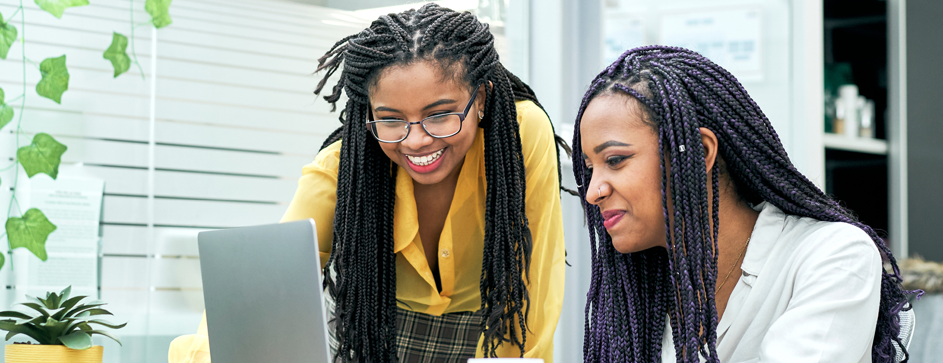 Two female employees smiling and looking at laptop