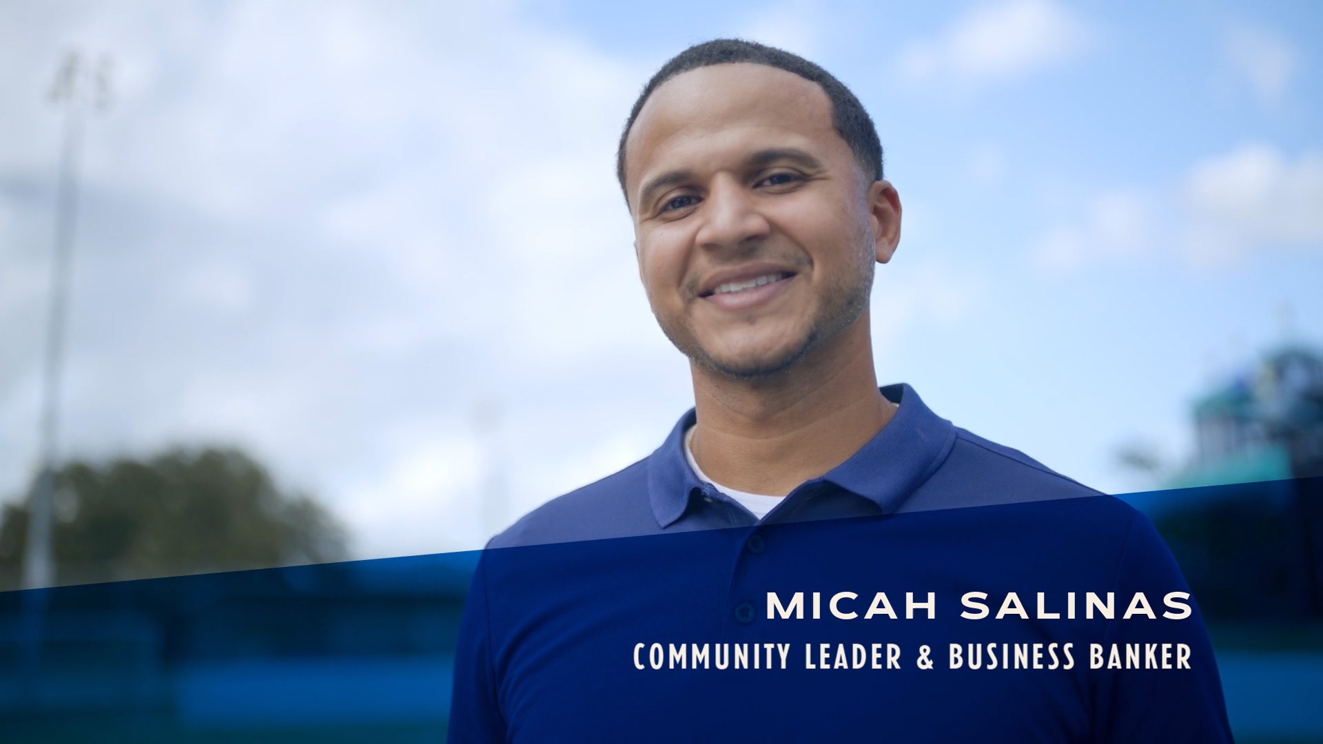 Initial video image of Micah Salinas Community Leader and Business Banker in a blue shirt on a football field