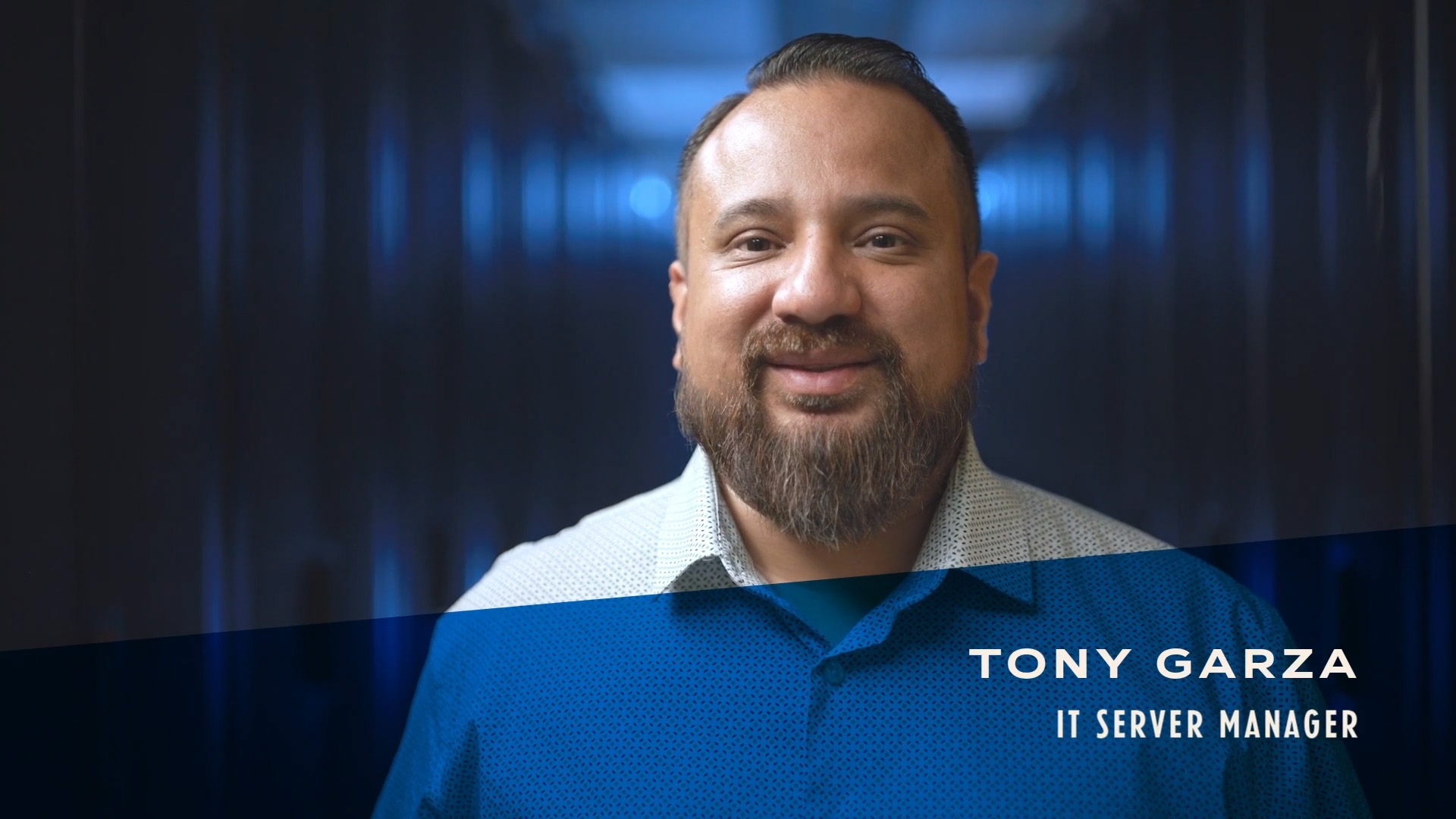 Initial video image of Tony Garza, IT Server Manager in a white/blue shirt with an IT server room in the background