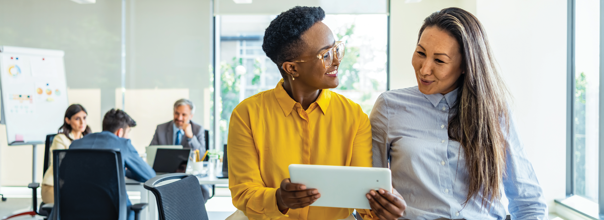 Two women talking and looking at a tablet.