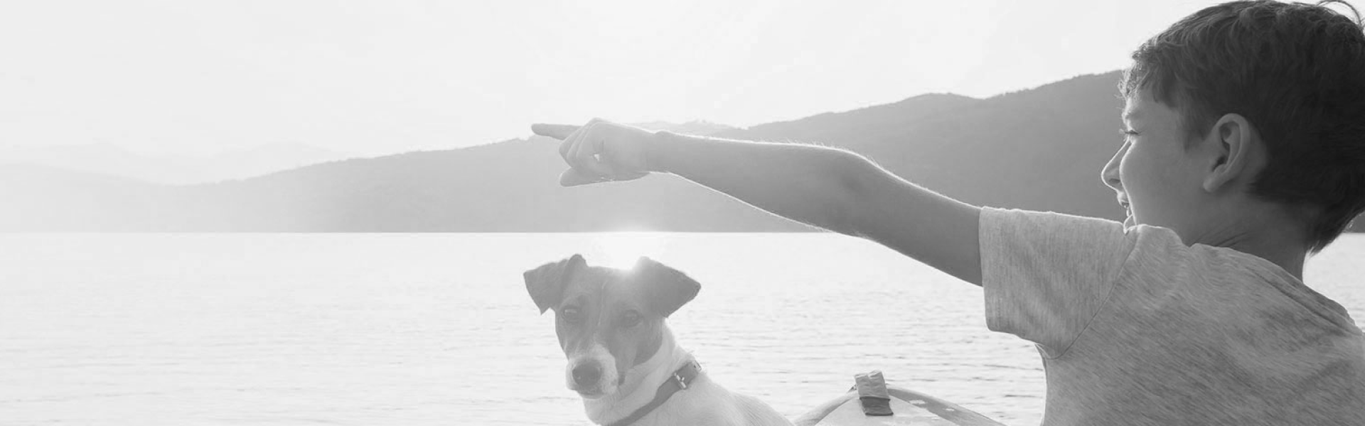 boy and dog in canoe pointing to mountain
