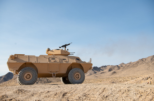Side view of a Textron Systems armored reconnaissance vehicle positioned in a rocky desert environment.