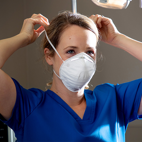 Nurse putting on a PPE dust mask