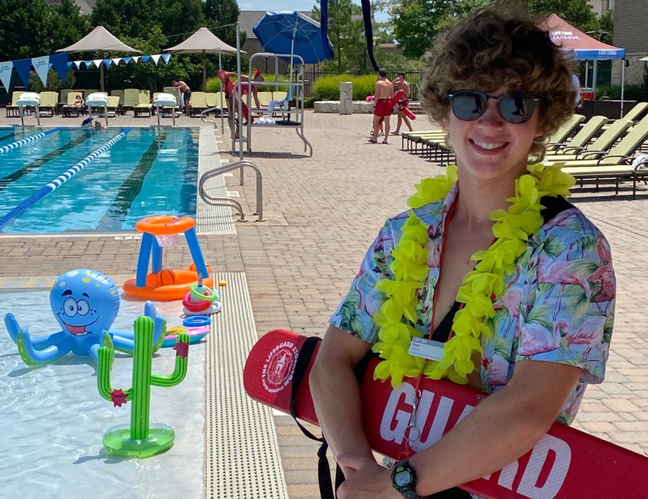 Life Time lifeguard dresses up in a tropical shirt at the Life Time pool for a kids event.