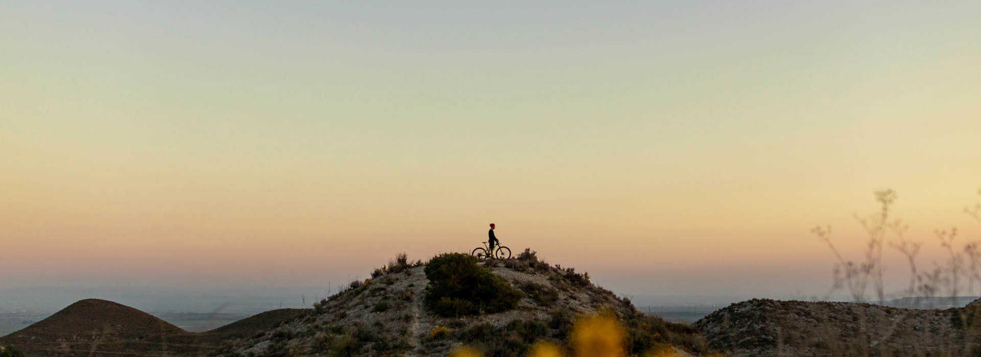 A biker on the hills with the sunset in the background.