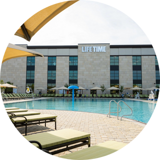 Back view of a Life Time club showing the outdoor pools and umbrellas.