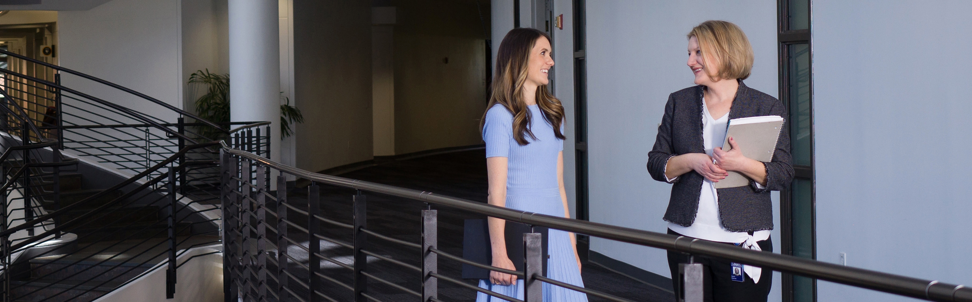 Two female associates walking and discussing work at corporate headquarters