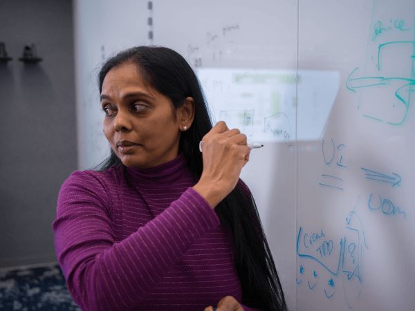 Tech associate writing on a whiteboard during a meeting