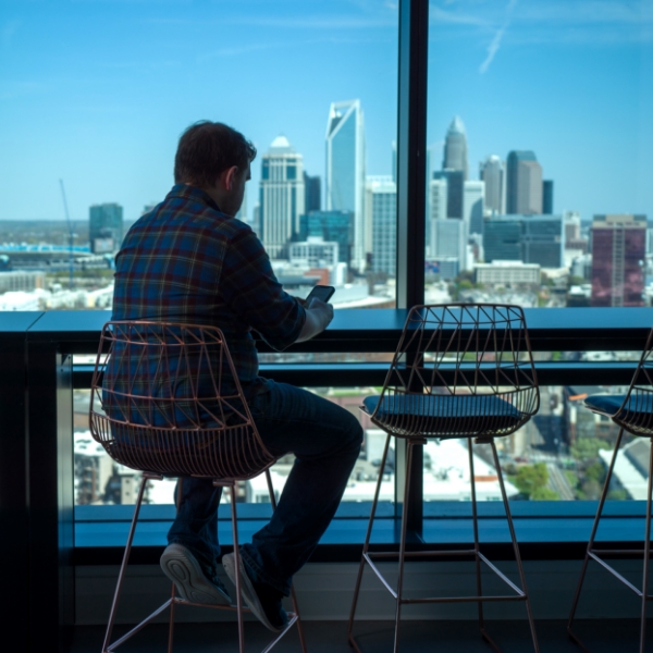 Male associate working in an open workspace with city visible in the background