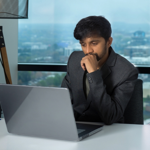 Male associate working on his laptop in his office