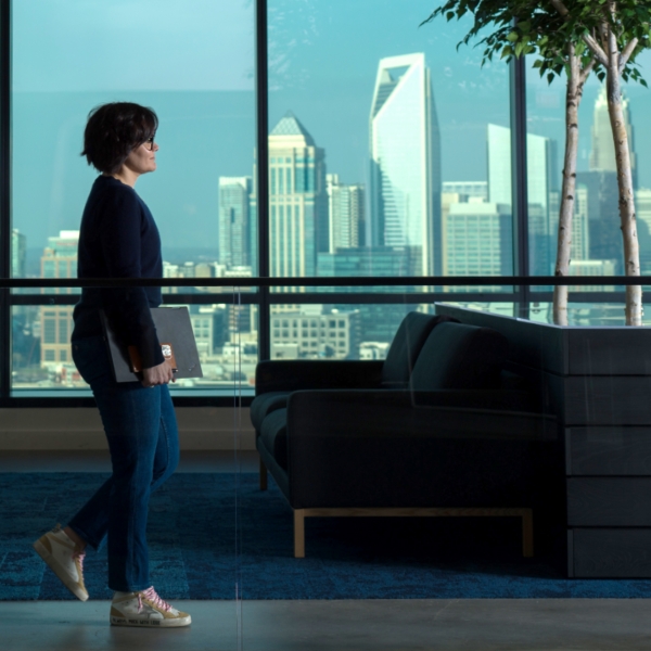 Female associate walking in the Tech Hub with the city visible in the background