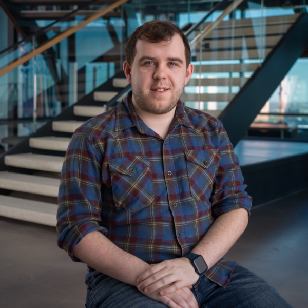 Male associate sitting by steps in the Tech Hub