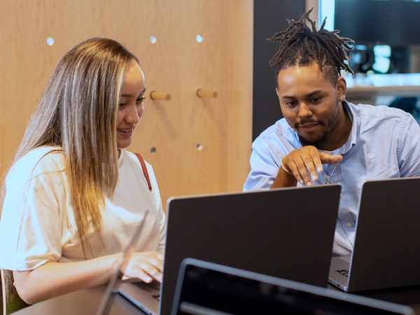 Two associates working on laptops in a conference room