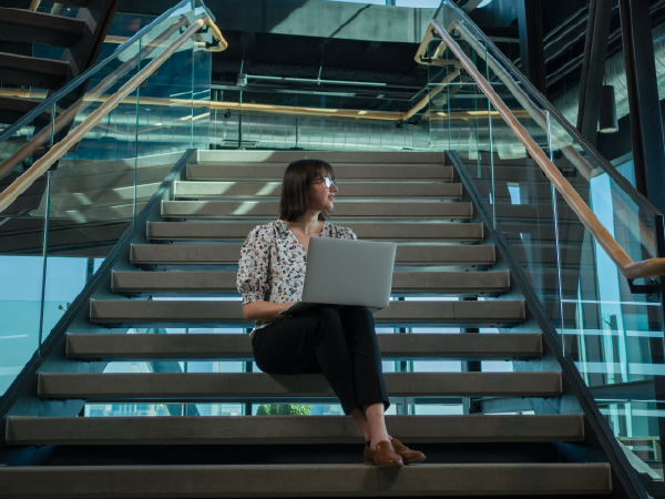 Female associate working on her laptop on the steps of the Tech Hub