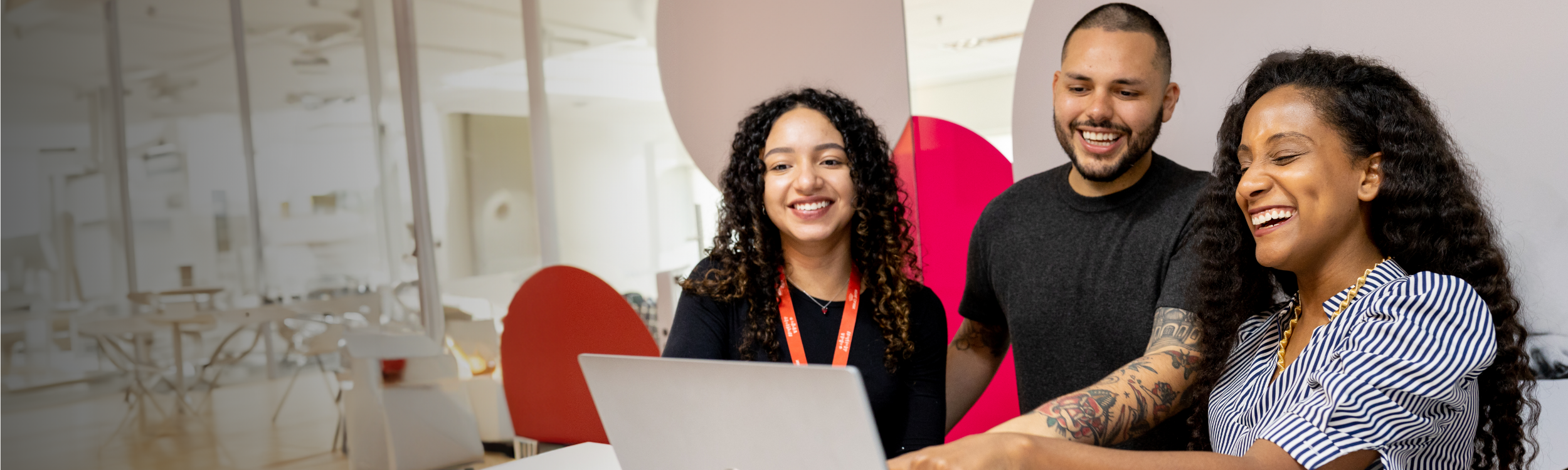 An image of three Mars Associates, laughing together in front of a laptop 