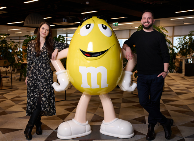 Image of two Associates sitting on a sofa, speaking to another Associate