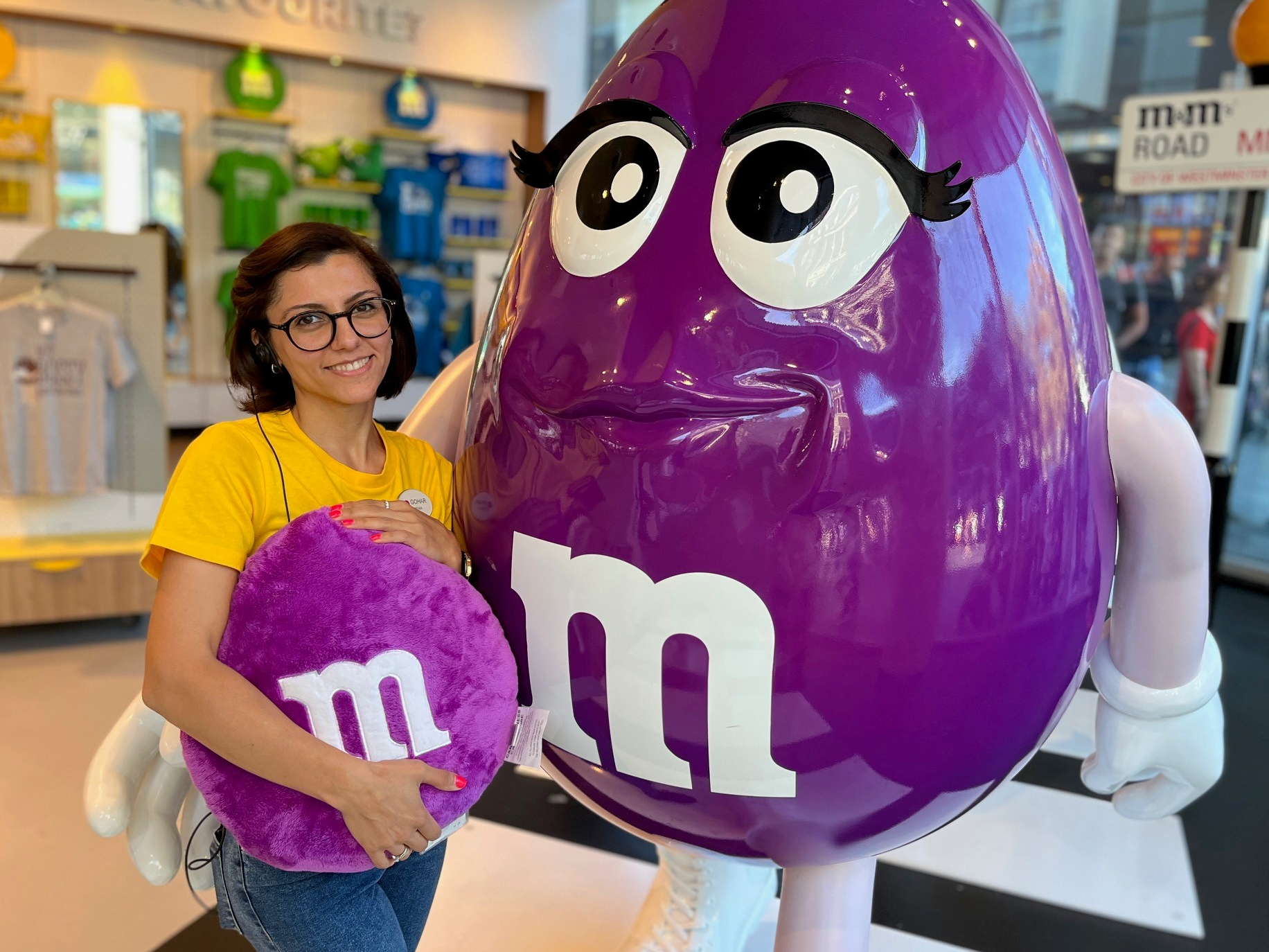 A image a Mars Associate posing with a life size M&M statue