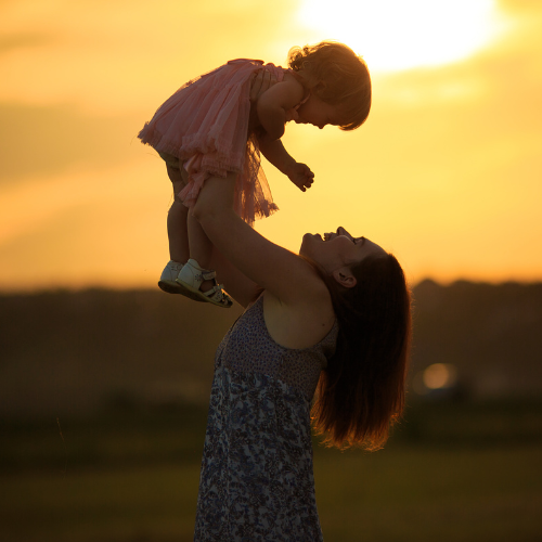 Woman smiling while looking at baby she is holding.