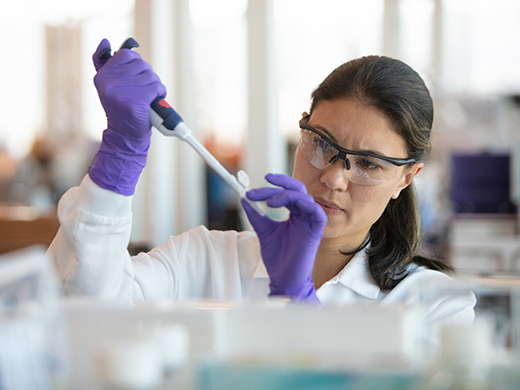 Woman wearing goggles and gloves working in science laboratory