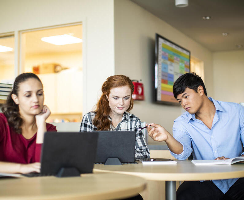 3 élèves dans une salle de classe regardant des ordinateurs portables
