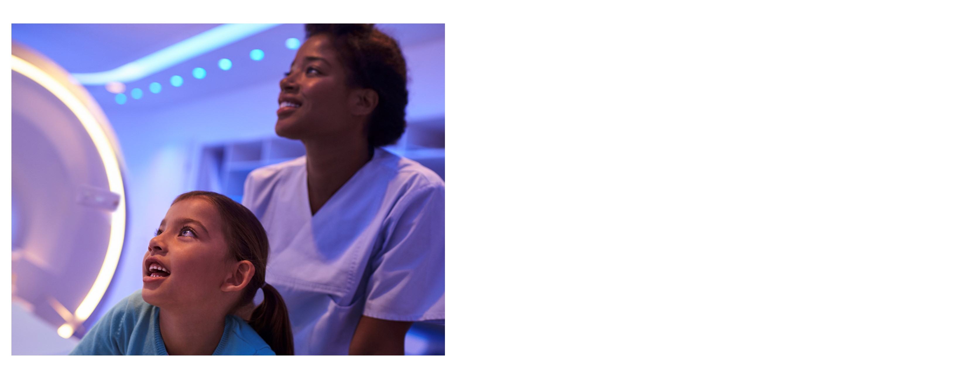 Doctor pushing little girl with pigtails in a wheelchair to a Philips MRI