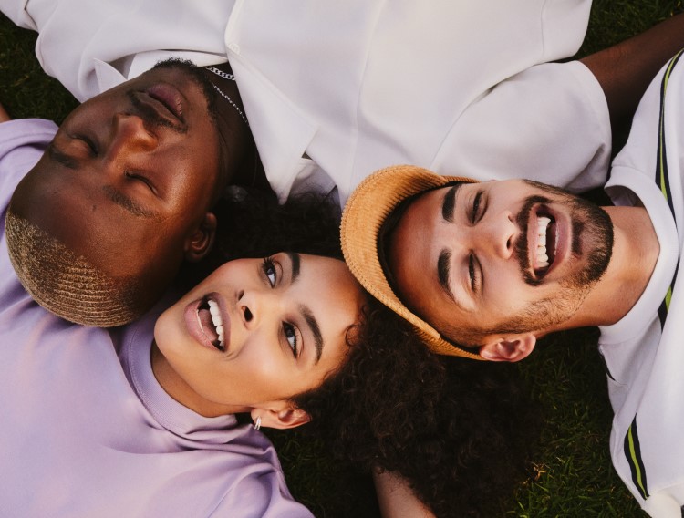Three people laying in grass