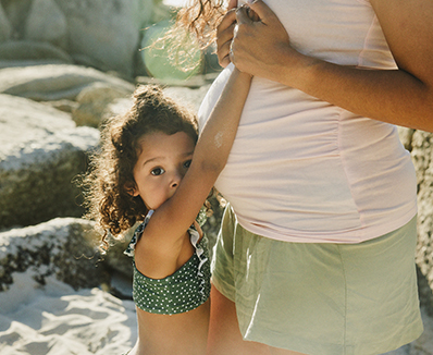 Una madre embarazada con su hija en la playa