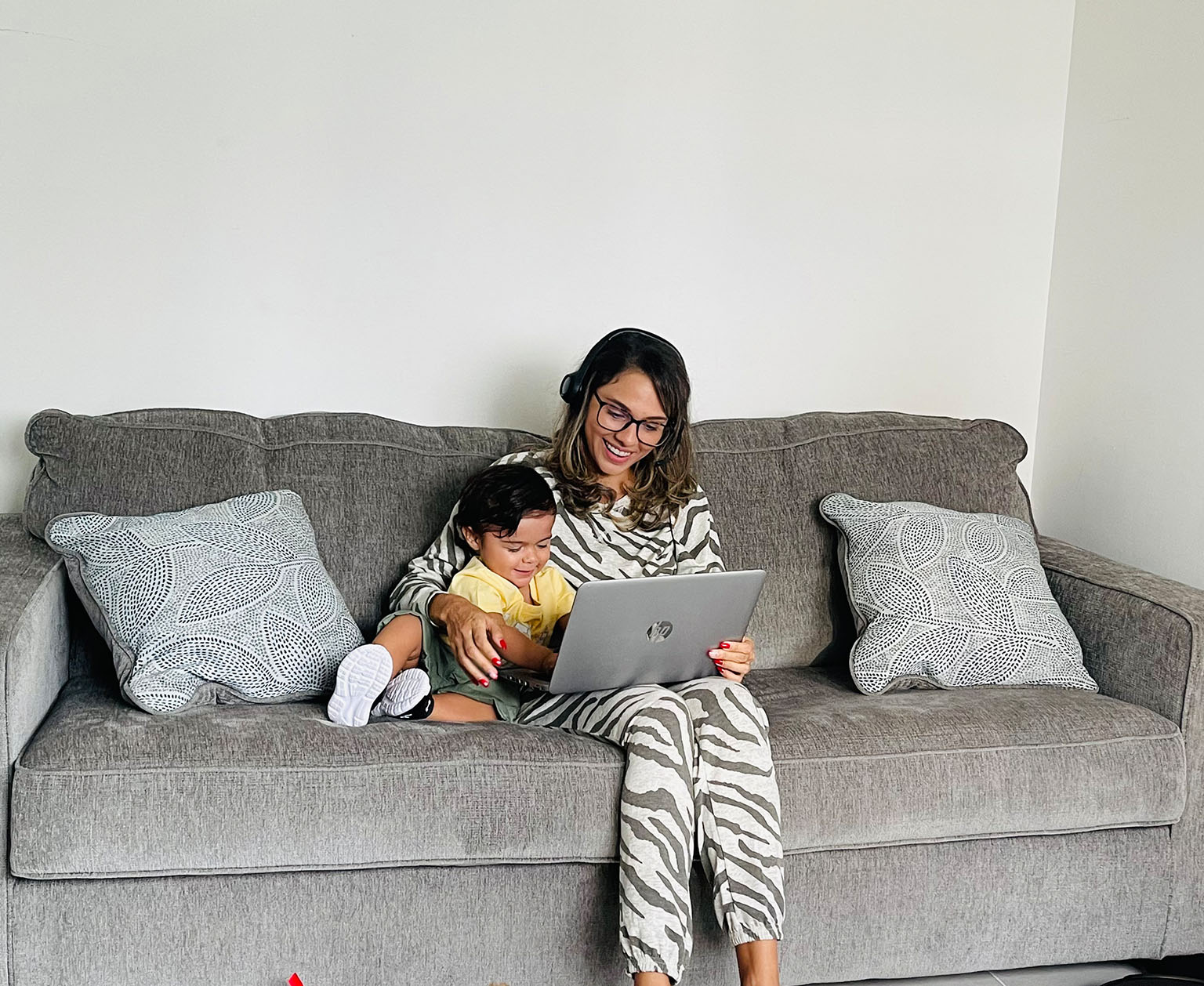 Una madre sentada en un mueble con su hijo y mirando la laptop
