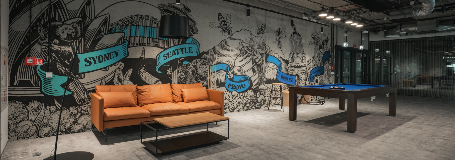 Image of the Qualtrics Kraków office with a leather couch, ping pong table, and mural. Overlayed is a search bar to explore roles and job opportunities.