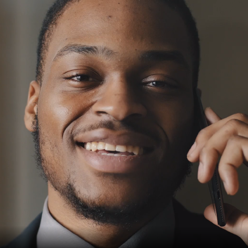 BIPOC man smiling on phone.
