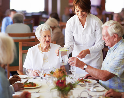 image of a male server smiling and holding a trade of food in a kitchen setting