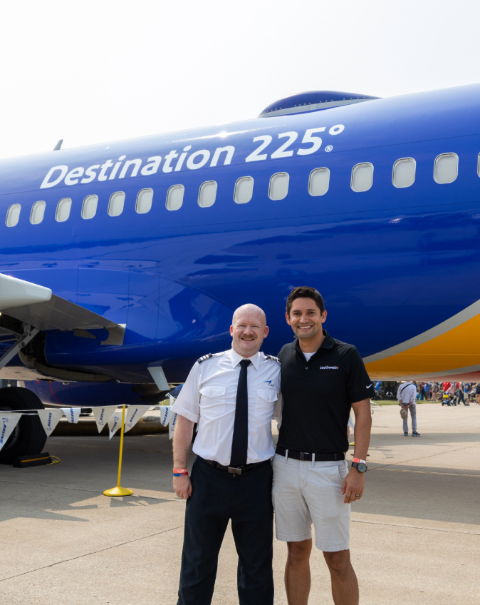 Matthew A. smiling in front of the Destination 225 aircraft