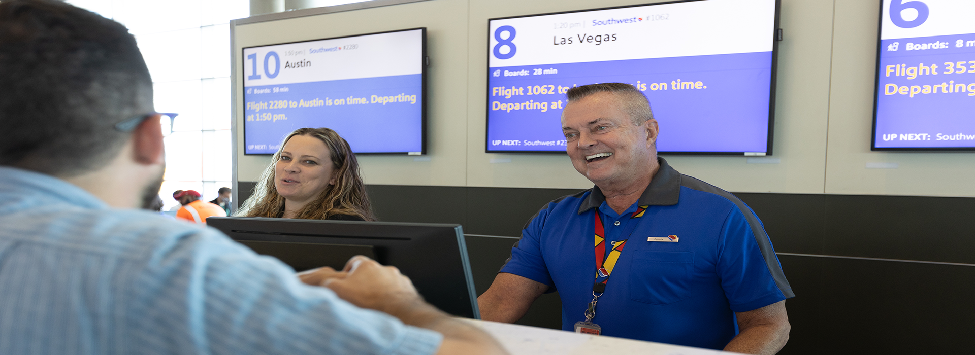 Customer Service Agents smiling at a Customer at the airport