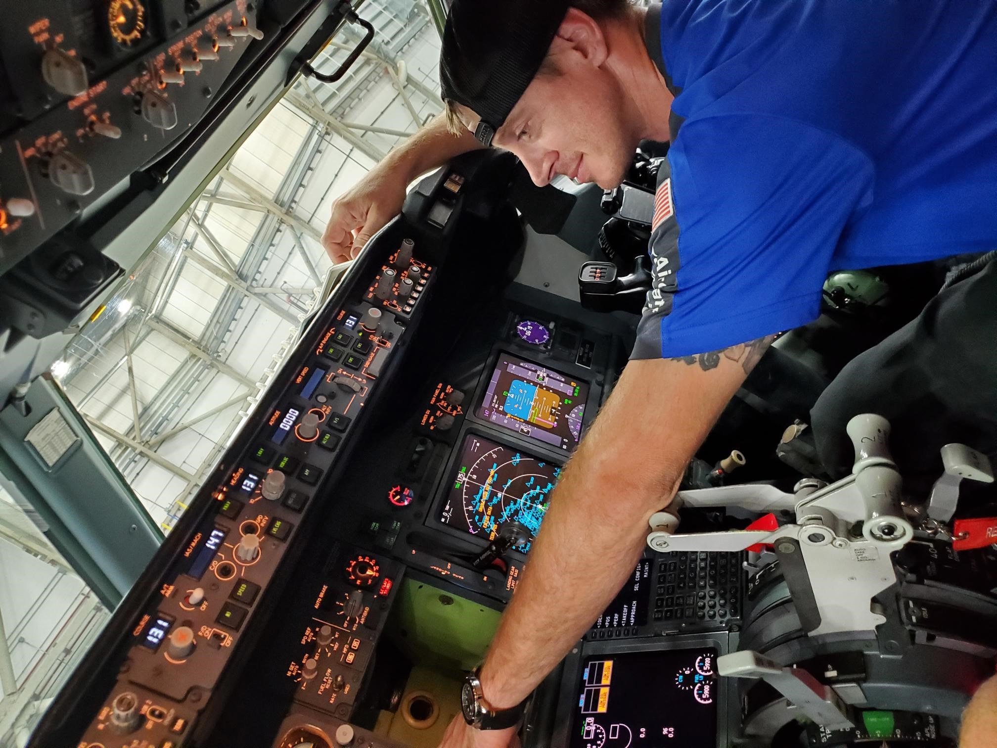 Clayton L. working and smiling inside an aircraft.