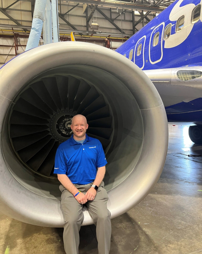 Matthew A. smiling with a Southwest aircraft