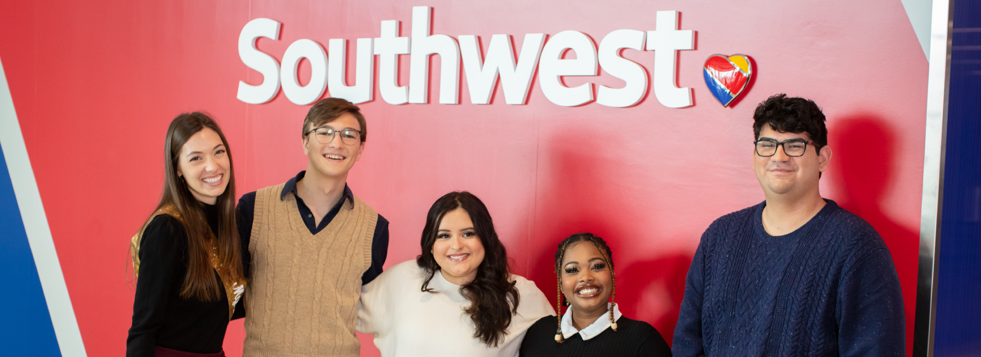 Young adults smiling in front of a Southwest sign