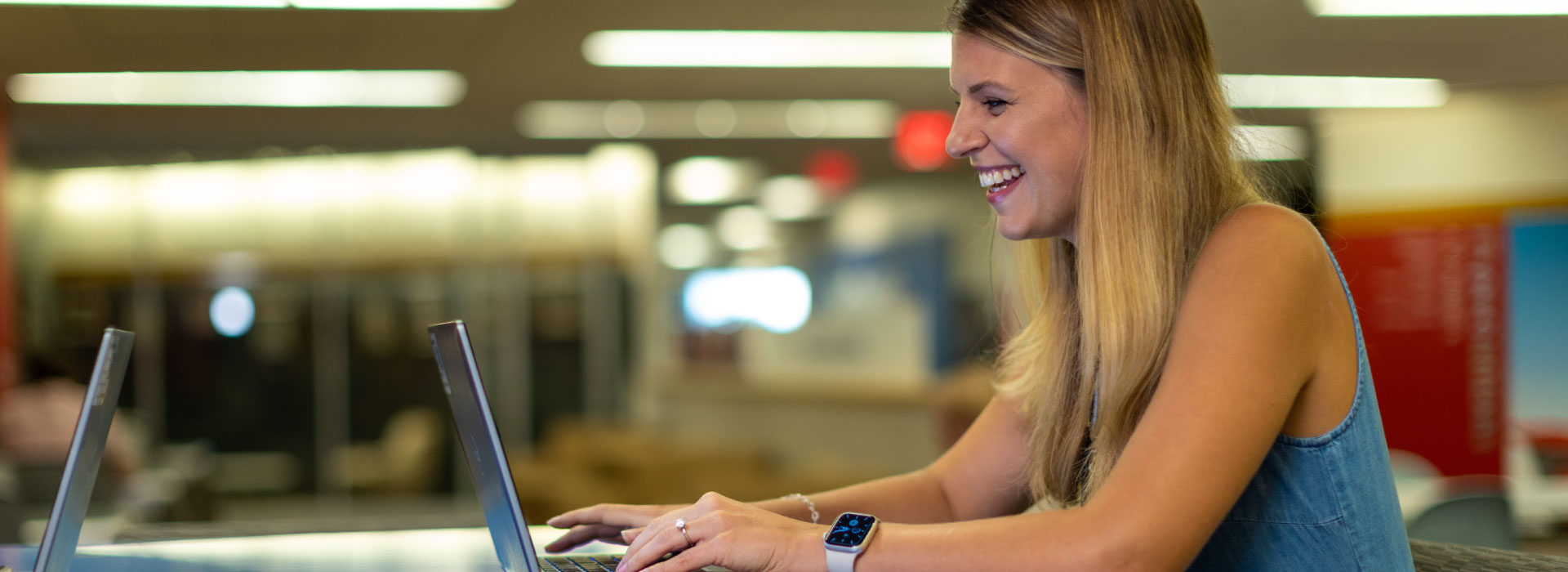 A woman smiling and sitting at her laptop