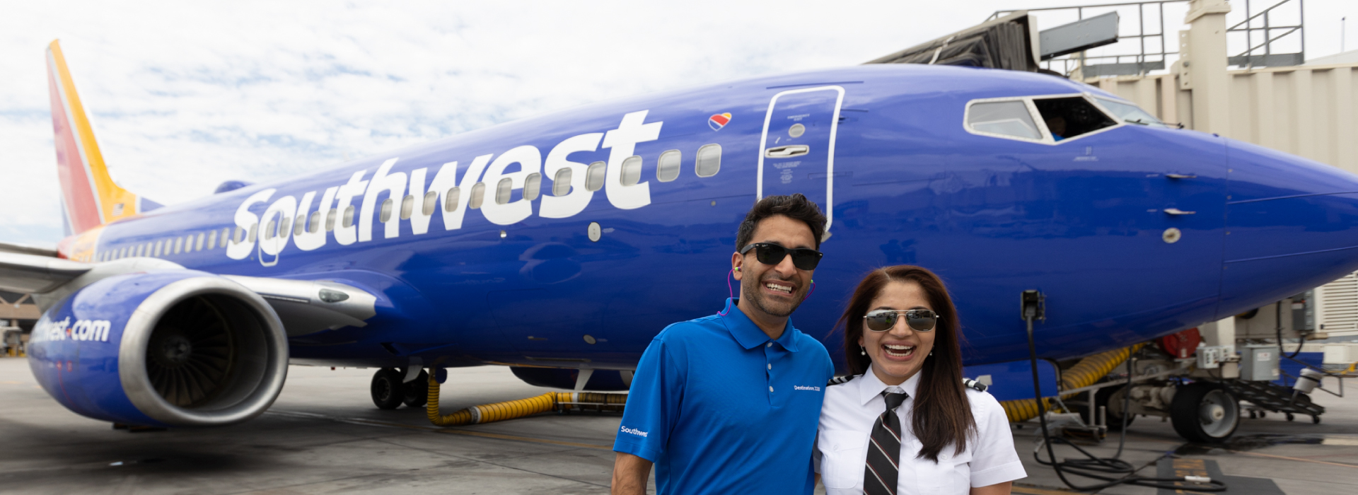 Pashi and his sister smiling in front of a Southwest plane