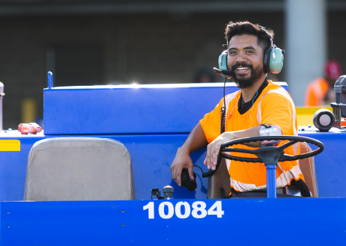 Ramp agent smiling and driving a luggage cart